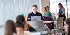 A student seated at a table working on their laptop