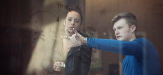 Engineering students observing and discussing data displayed on a whiteboard